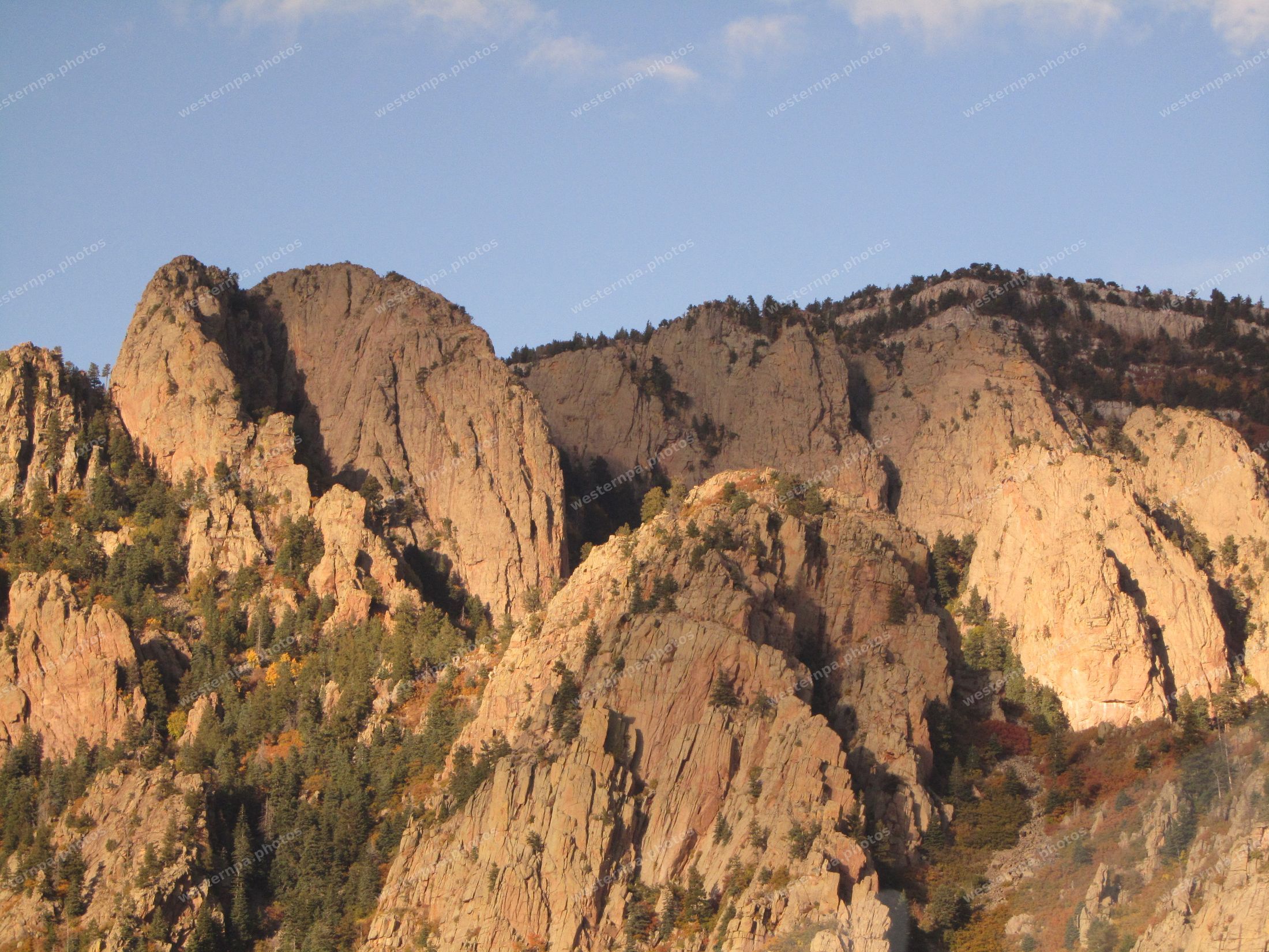 Golden evening light on rugged granite peaks dotted with conifers