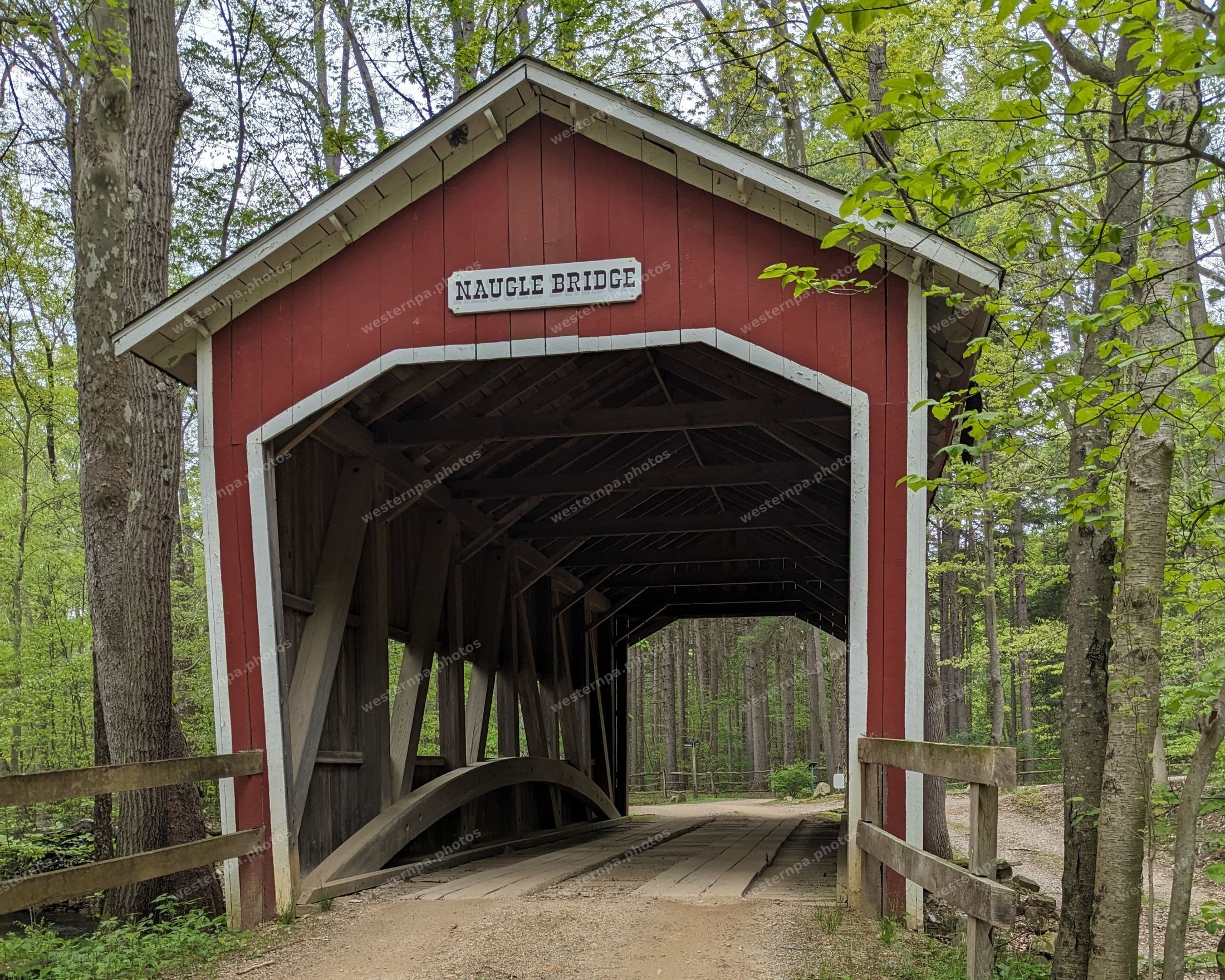 Front view of the red Naugle covered bridge with its name sign