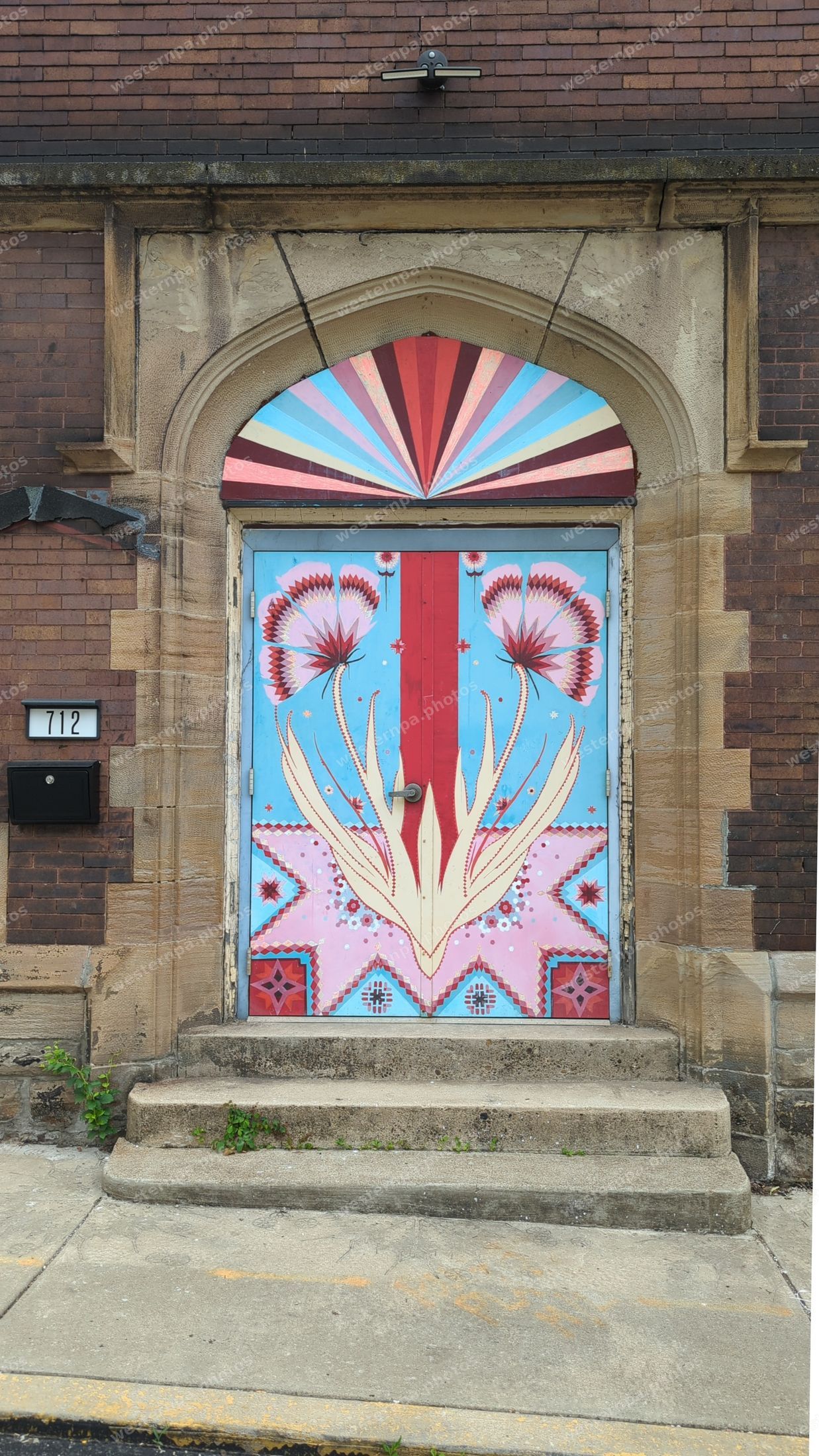 Ornately hand-painted door with a floral sunburst design on a brick building