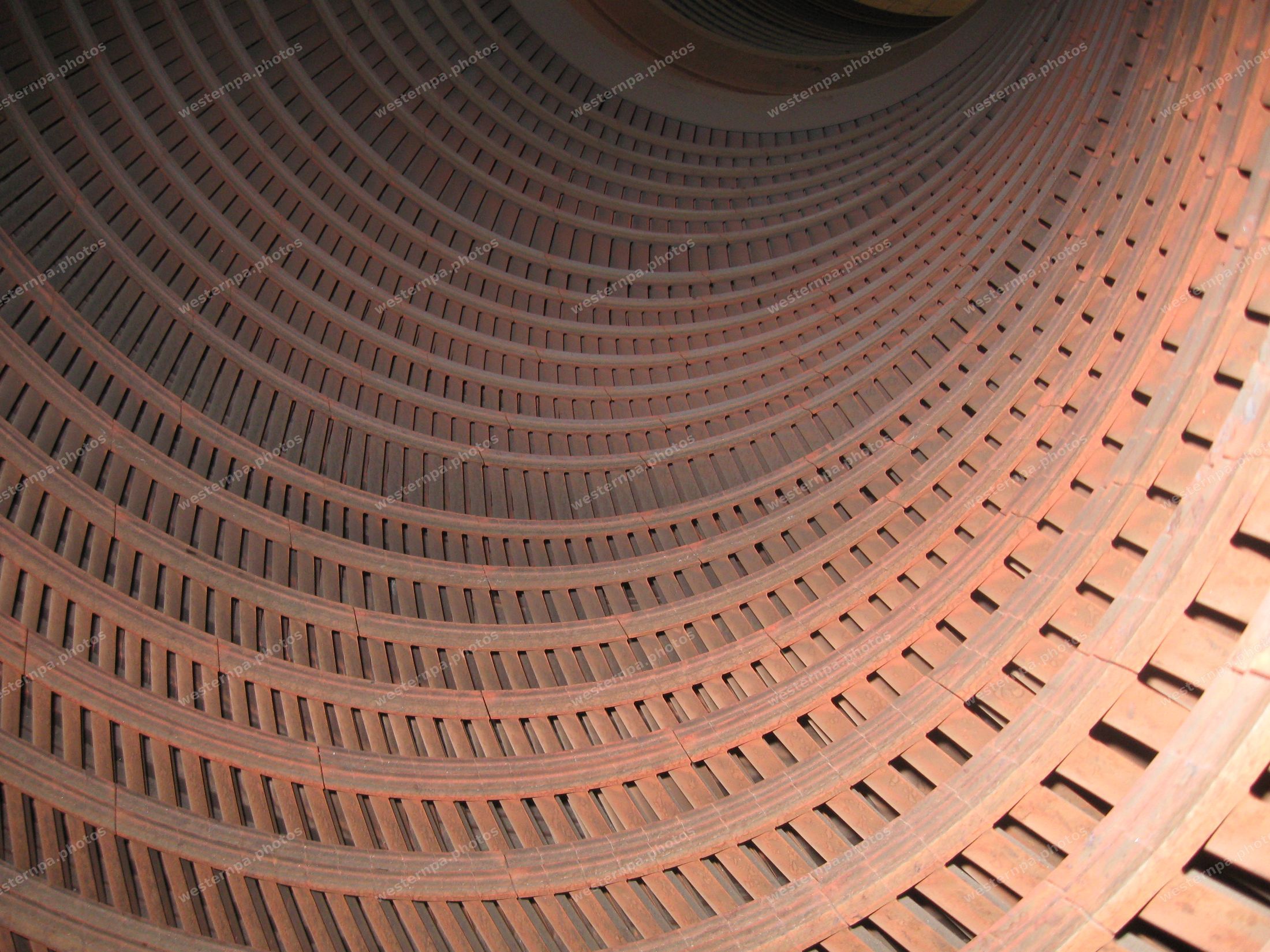 Abstract concentric rings of rusted riveted steel curving into darkness